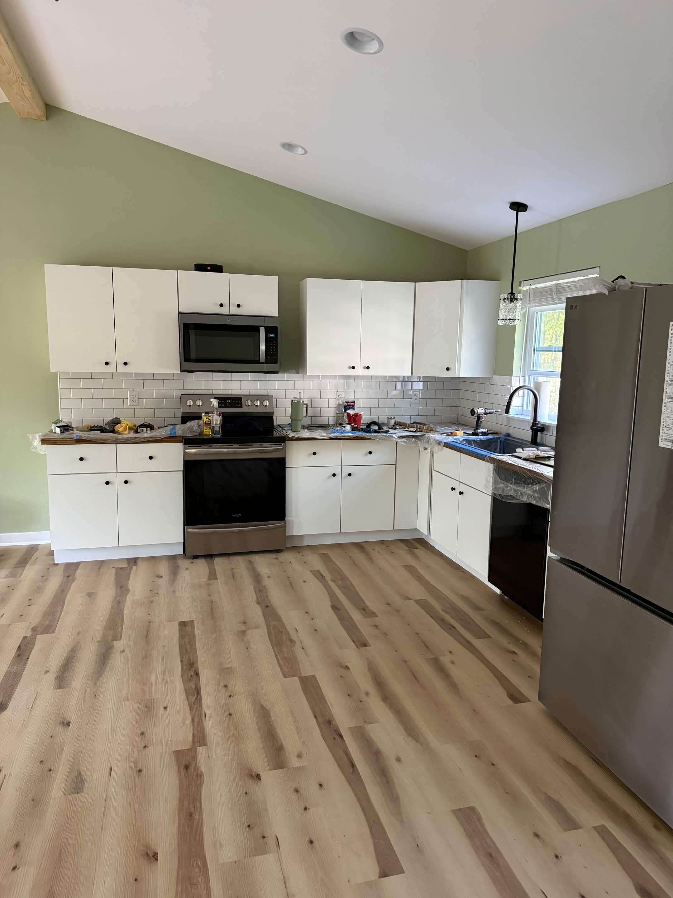 Finished kitchen with white cabinets, stainless appliances, and subway tile backsplash