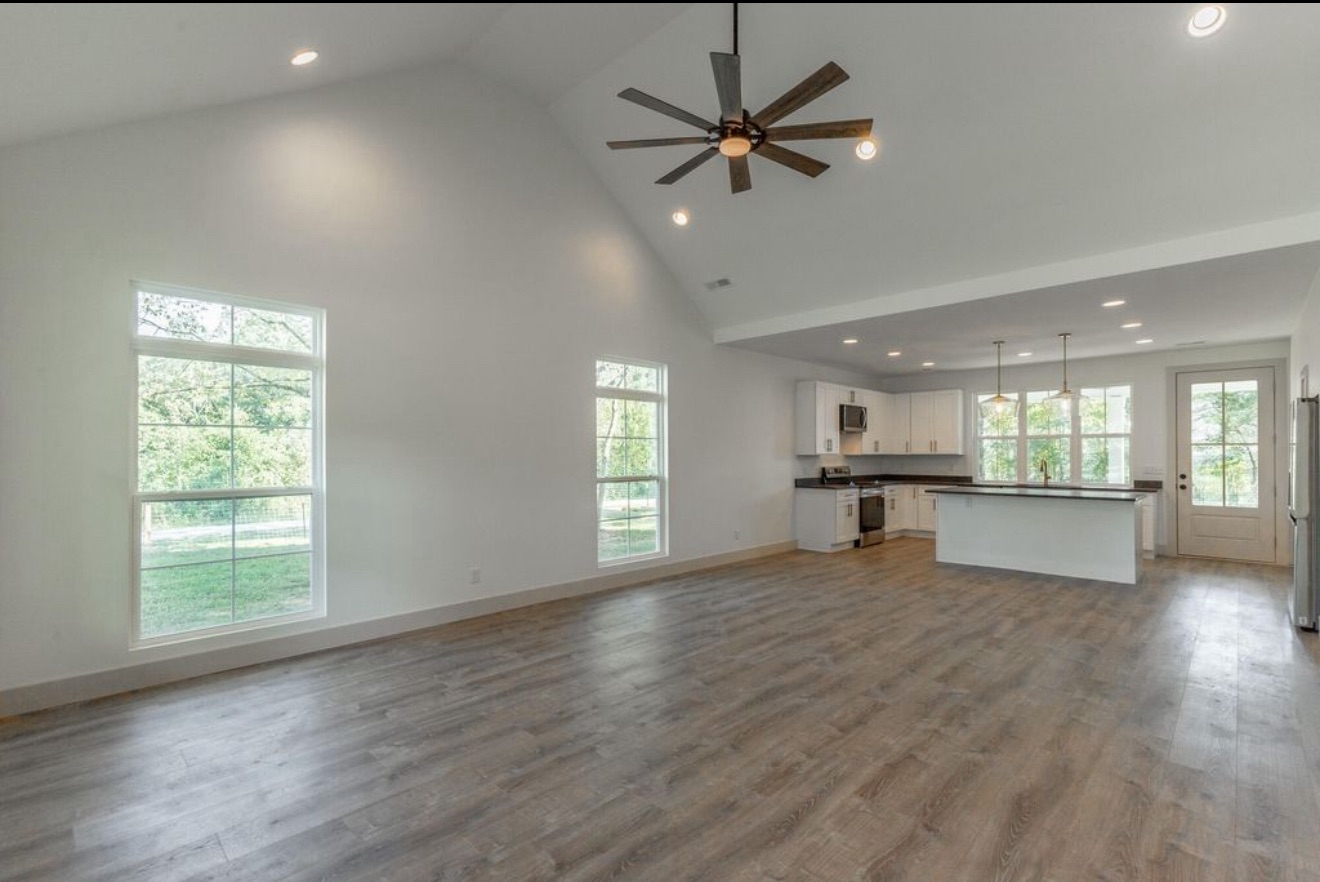 Finished room with vinyl plank flooring, ceiling fan, and kitchen appliances